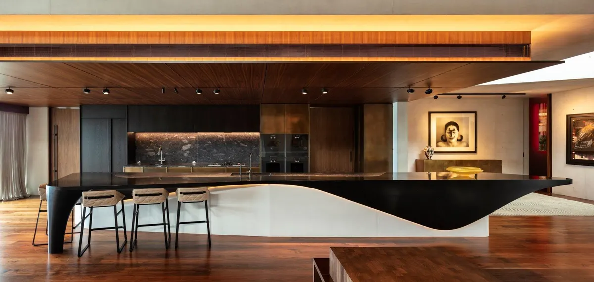 Îlot de cuisine sculptural en solid surface noir et blanc sous un plafond en bois éclairé